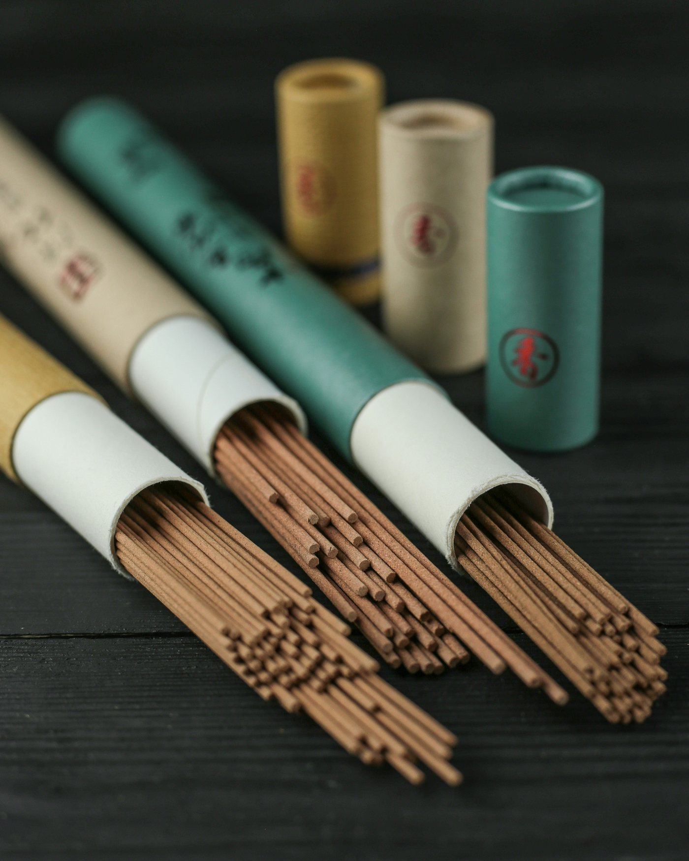 A bundle of slim Japanese incense sticks spilling from paper tubes