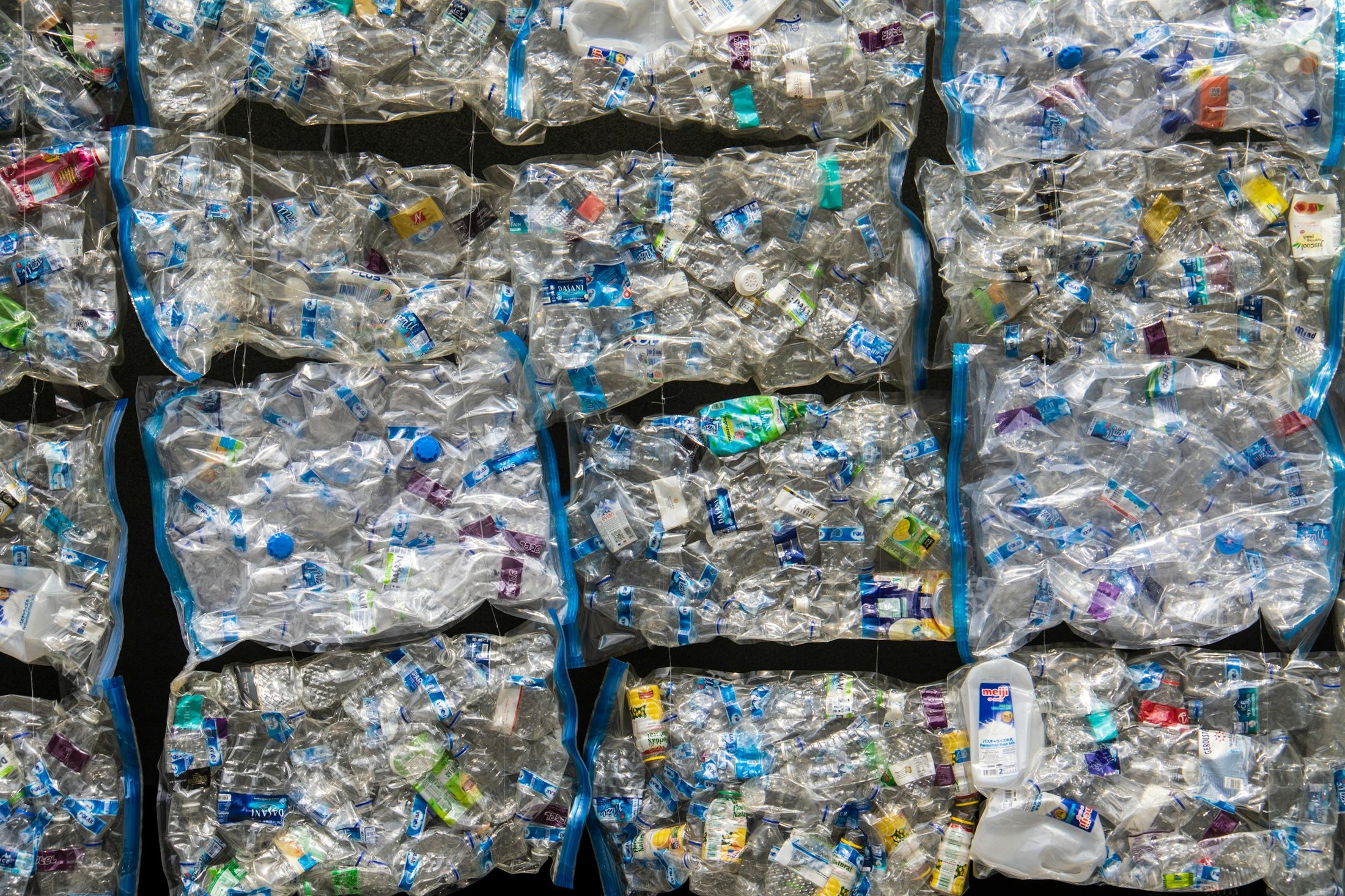 Bales of crushed clear plastic bottles stacked for recycling