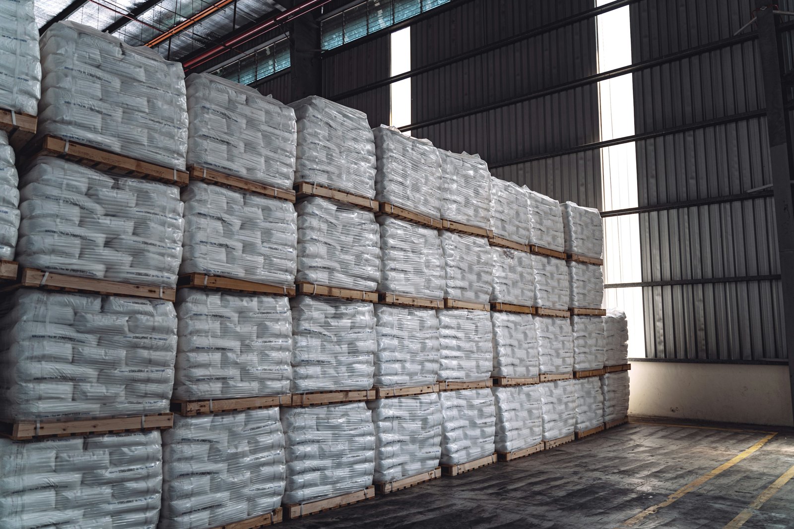 Pallets of white plastic resin bags stacked in a warehouse