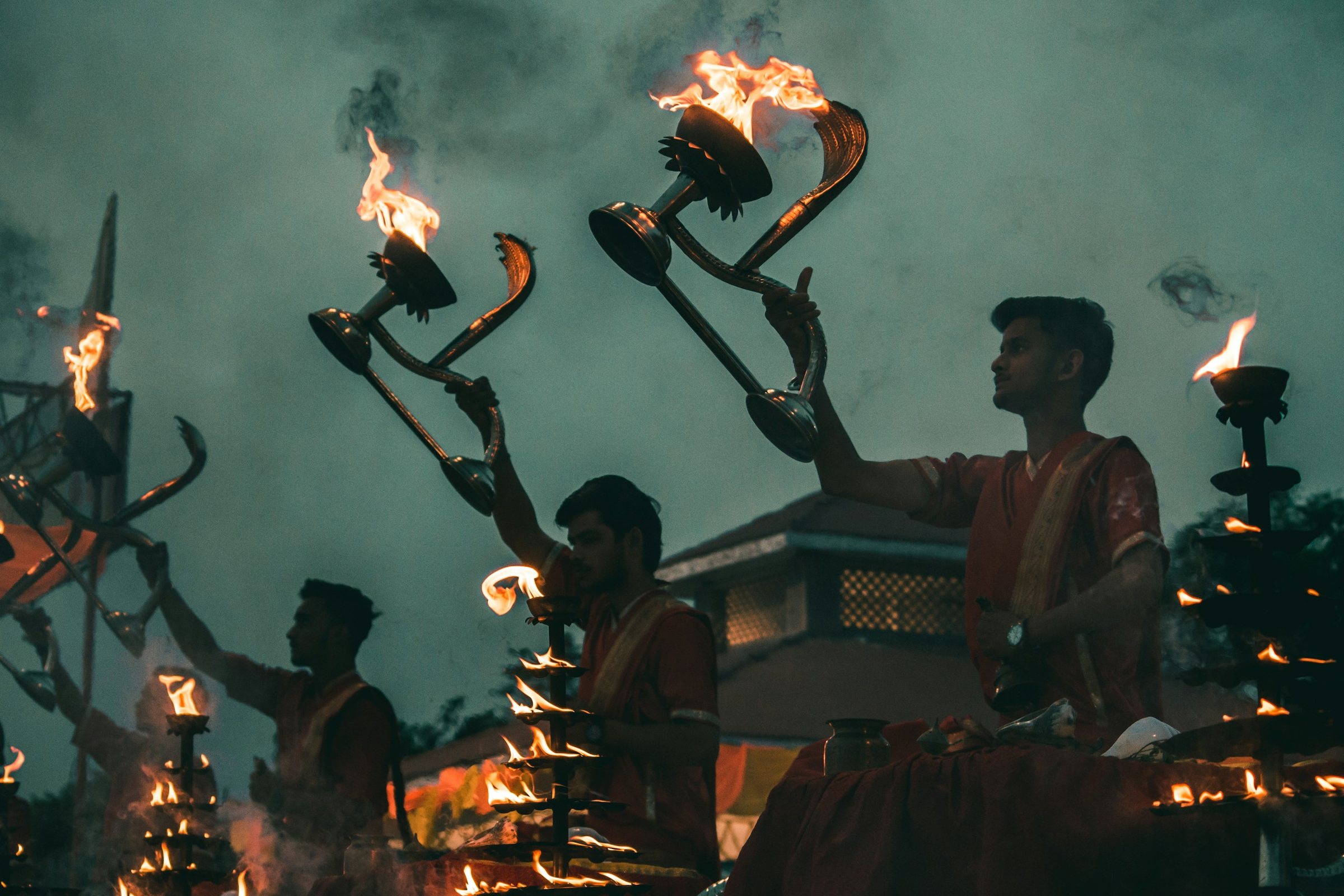 Priests raising flaming lamps during the evening aarti on the Ganges at Varanasi