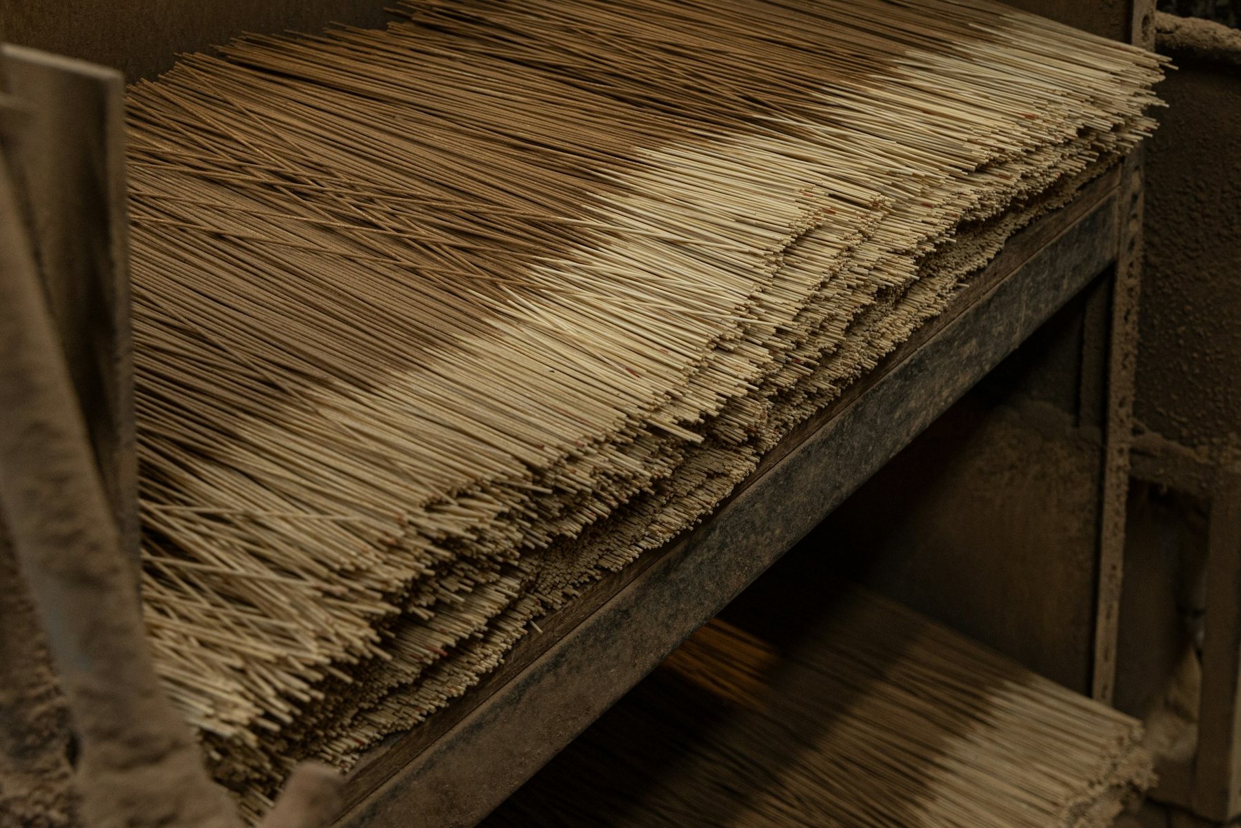 Stacks of raw, unscented incense sticks drying on a wooden rack
